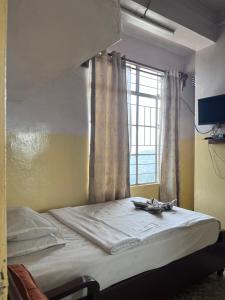 Bett in einem Zimmer mit Fenster in der Unterkunft JN Hotel in Kohīma