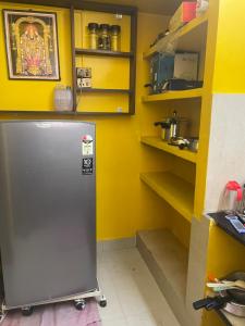 Una cocina amarilla con refrigerador y estantes. en HOME STAY in ground floor, en Chennai