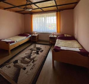 a room with two beds and a window and a rug at Willa Koniaków in Koniaków