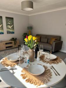 einen Tisch mit Tellern, Weingläsern und Blumen darauf in der Unterkunft Bright and spacious two bed apartment with roof terrace in Hoddesdon in Hoddesdon