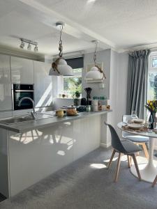 cocina con armarios blancos, mesa y silla en Bright and spacious two bed apartment with roof terrace in Hoddesdon en Hoddesdon