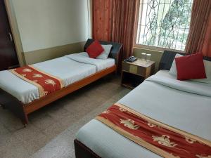 a hotel room with two beds and a window at Riverview Guest House in Guwahati