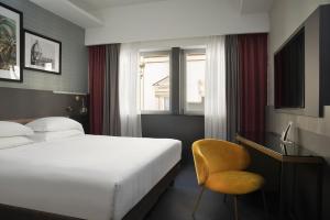 um quarto de hotel com uma cama e uma cadeira amarela em iQ Hotel Firenze em Florença