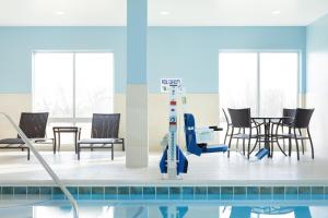 a swimming pool with chairs and a table in a room at Holiday Inn Express Fremont, an IHG Hotel in Fremont