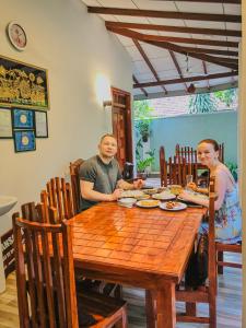mężczyzna i kobieta siedzący przy drewnianym stole w obiekcie Nehansa Resort and safari w mieście Tissamaharama