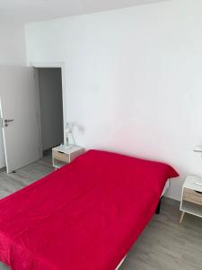 un grande letto rosso in una stanza bianca di CASA ANALUCIA a Faro