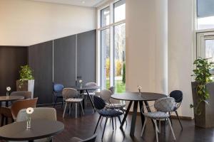 ein Restaurant mit Tischen, Stühlen und Fenstern in der Unterkunft NH München Airport in Oberding