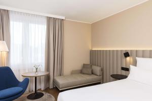 ein Hotelzimmer mit einem Bett und einem Sofa in der Unterkunft NH München Airport in Oberding