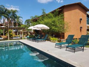 a pool with chairs and an umbrella next to a house at Confraria da Prata Flats in Pirenópolis