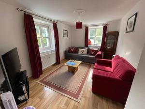 ein Wohnzimmer mit einem roten Sofa und einem Tisch in der Unterkunft Alpine Blue Apartments in Griesen