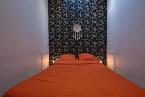 - une chambre avec un lit orange et un mur noir dans l'établissement Maisonnette Haut de Gamme proche de Disneyland et de Paris, à Neufmontiers-lès-Meaux