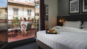 una donna seduta su un letto in una stanza d'albergo di iQ Hotel Firenze a Firenze