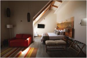 um quarto com uma cama e uma cadeira vermelha em Hotel casa Solaria em Pucón