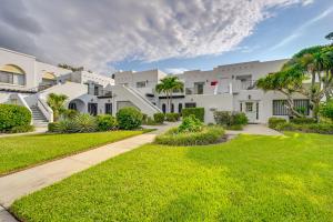 una hilera de edificios blancos con palmeras y césped en Lovely Naples Vacation Rental with Shared Pools!, en Naples