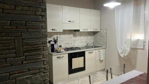 a kitchen with white cabinets and a brick wall at Casa di Paola in Asti