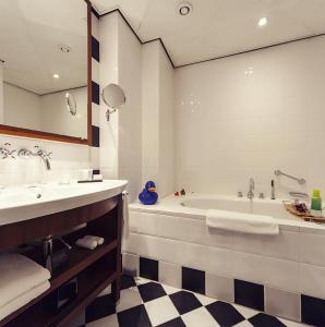 ein Badezimmer mit einer Badewanne, einem Waschbecken und einem Spiegel in der Unterkunft Banks Mansion - All Inclusive Boutique Hotel in Amsterdam
