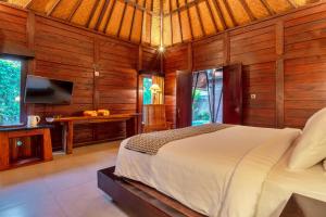 1 dormitorio con 1 cama en una habitación de madera en Sri Abi Ratu Villas, en Sukawati