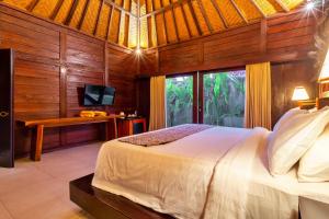 a bedroom with a bed and a desk and a television at Sri Abi Ratu Villas in Sukawati