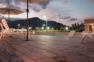 une terrasse avec des chaises et un parasol ainsi qu'une piscine dans l'établissement Casa Adela - Cabañas Resort, à La Rioja