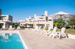 a group of chairs and umbrellas next to a swimming pool at Casa Adela - Cabañas Resort in La Rioja