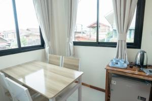 a table and chairs in a room with windows at Chotika Hotel โรงแรมโชติกา ณ เชียงคาน in Chiang Khan