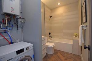 a bathroom with a tub and a toilet and a washing machine at Cozy Apartment in Historic OTR in Cincinnati