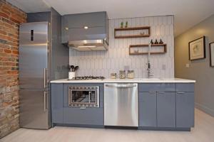 a kitchen with blue cabinets and a stainless steel refrigerator at Cozy Apartment in Historic OTR in Cincinnati