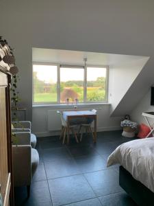 a room with a table and two windows and a bed at De Moeraseik in Zele