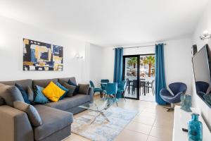 a living room with a couch and a table with chairs at Paloma Beach Apartments in Los Cristianos