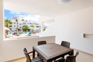 a dining room with a table and chairs and a pool at Paloma Beach Apartments in Los Cristianos