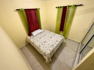 a small bed in a room with green and red curtains at house on the hill in Nagua