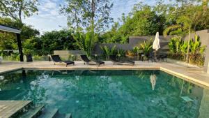 a swimming pool with two chairs and a swimming pool at Villa Obsidian, with staff, sea view and walk to Choeng Mon beach in Choeng Mon Beach