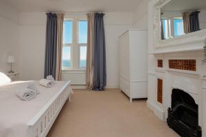 a white bedroom with two beds and a fireplace at Ventnor Views in Ventnor