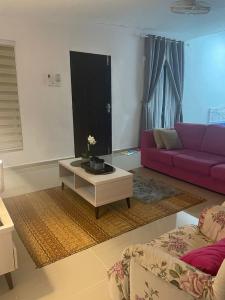 Sala de estar con sofá púrpura y mesa de centro en Lala Homestay 1, en Kuala Terengganu