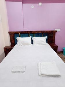 a large white bed with two white towels on it at Hotel A R S in Patna