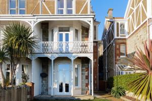 a white house with a balcony and palm trees at Ventnor Views in Ventnor