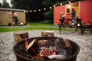 a fire pit in a yard with people in the background at The Hamlet at Samlesbury Hall in Balderstone