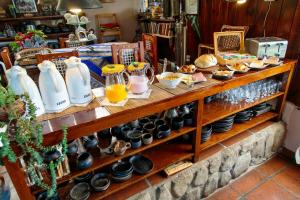 un estante lleno de platos y jarras de zumo de naranja en Posada La Soñada en Tafí del Valle
