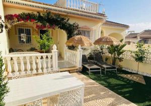 a house with a white porch with umbrellas at Casa la Pajarera in Ciudad Quesada