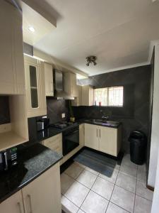a kitchen with white cabinets and a black wall at HomeSweetHome City Apartment in Nelspruit