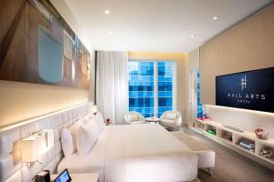 a hotel room with a large white bed and a tv at HALL Arts Hotel Dallas, Curio Collection by Hilton in Dallas