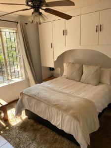 a bedroom with a bed with a ceiling fan and a window at HomeSweetHome City Apartment in Nelspruit