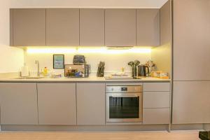 a kitchen with white cabinets and a stove at Luxury Apartment - Close to City Centre - Free Parking, Fast Wifi, SmartTV with Sky and Netflix by Yoko Property in Milton Keynes