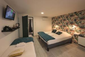 a bedroom with two beds and a tv on the wall at Hotel De La Crois&eacute;e in Poncin