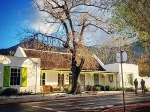 una casa blanca con un árbol delante en Greyton Toad Hall Guesthouse - individual rooms, en Greyton