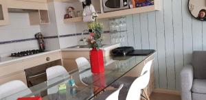 a glass table in a kitchen with a vase with flowers at Laguna Bahía departamento 5 personas maravilloso amoblado y decorado in Algarrobo