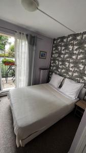 een slaapkamer met een groot bed en een raam bij Hôtel Marie Louise in Enghien-les-Bains