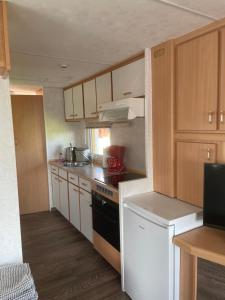 a kitchen with white cabinets and a stove top oven at Fischerhütte III Mobilheim in Polchow