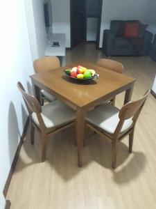een houten tafel met stoelen en een fruitschaal erop bij Flat com serviços em Blumenau-PM in Blumenau