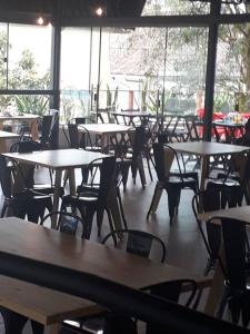 een leeg restaurant met tafels, stoelen en ramen bij Flat com serviços em Blumenau-PM in Blumenau